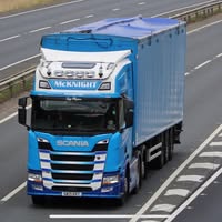 Blue McKnight Scania and bulk trailer travelling on a main road