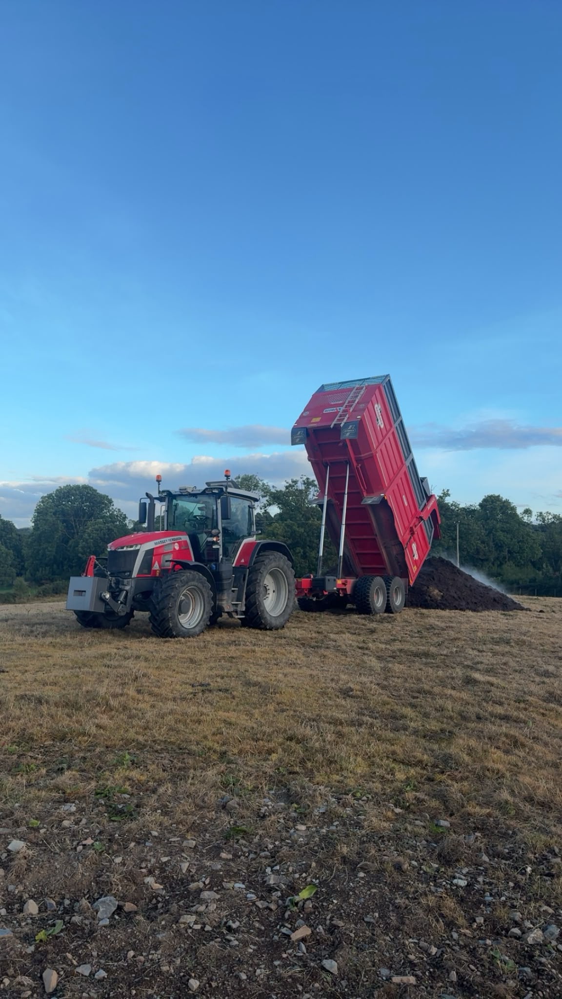 Massey Ferguson tractor with a raised Redrock tipper trailer in a field